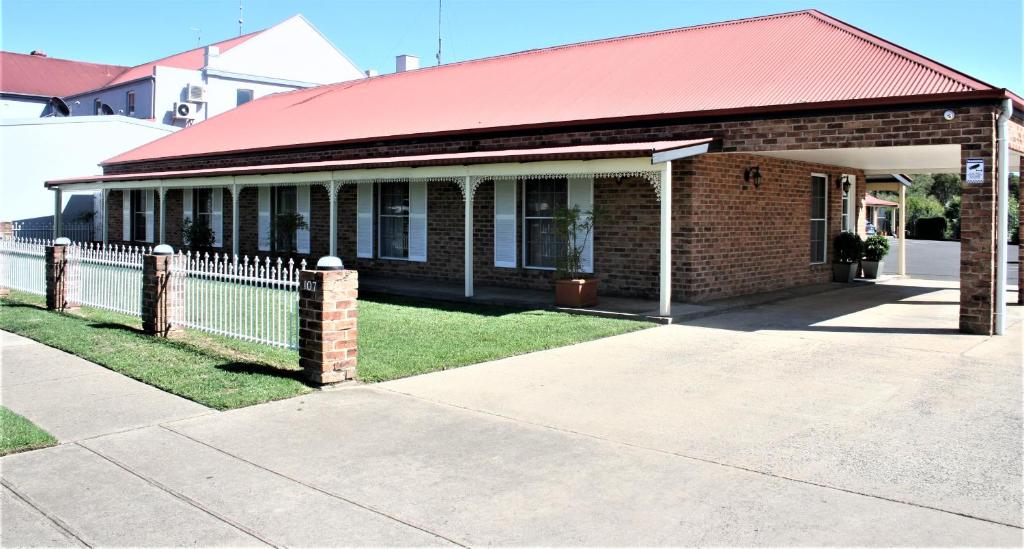 a brick building with a red roof and a fence at Club Motel Armidale in Armidale
