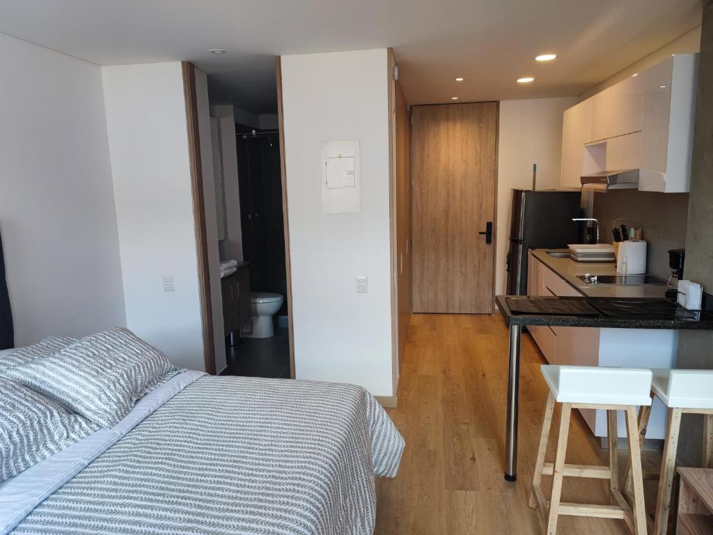 1 dormitorio con cama, mesa y cocina en Aparta Suite - Centro Internacional - Mitika, en Bogotá