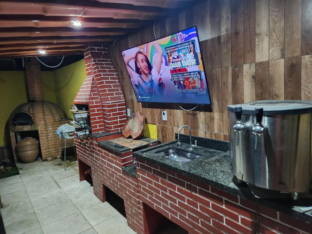 een keuken met een wastafel en een tv aan de muur bij POUSADA FLOR DO CARIBE in Rio das Ostras