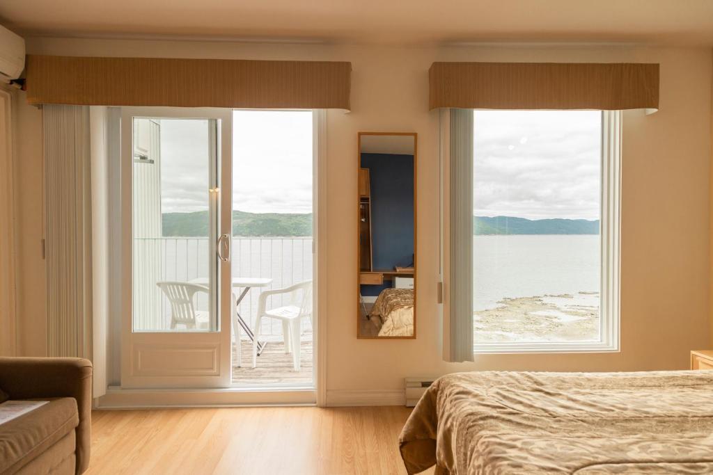 a bedroom with a bed and a view of the ocean at Auberge de la Rivière Saguenay in La Baie
