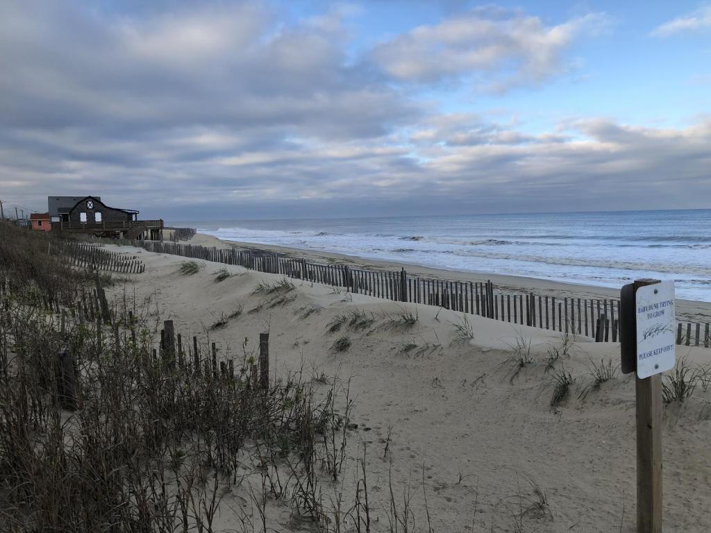 a beach with a fence and a house and the ocean at Queen Anne's Revenge at the Beach cottage in Kitty Hawk