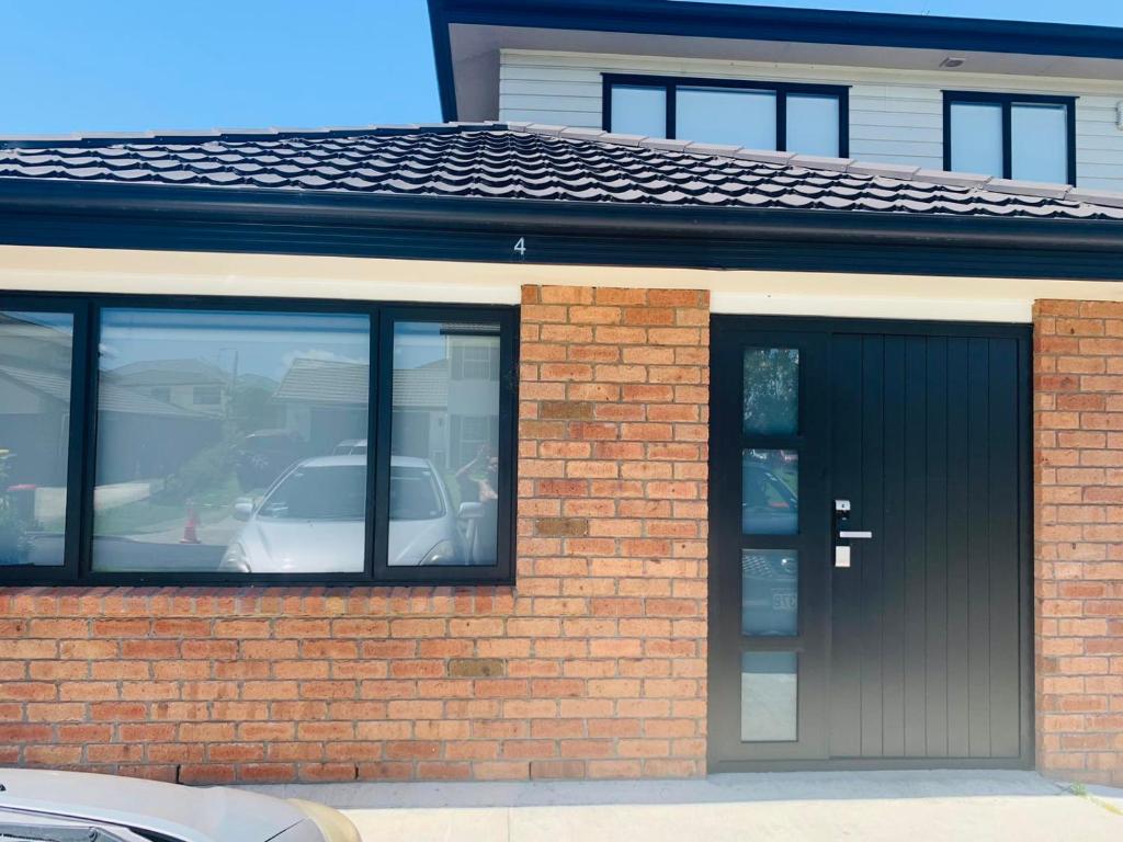 a red brick building with a black garage at 3 Bedroom Holiday Apartment Peninsula Park in Auckland