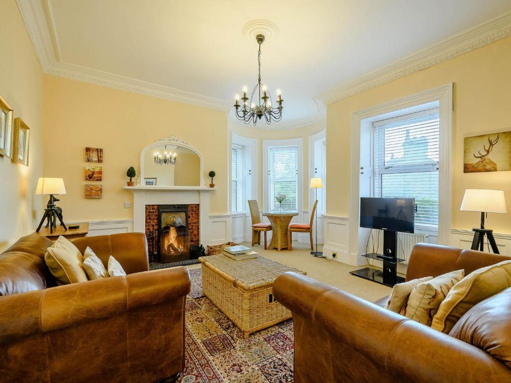 a living room with leather furniture and a fireplace at Meadow House Apartment in Moffat