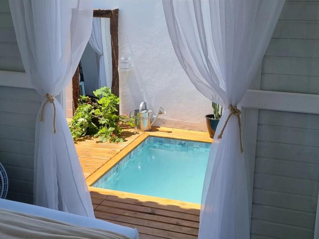 a swimming pool seen through a window with curtains at A Casinha de Madeira in Balneário Gaivotas