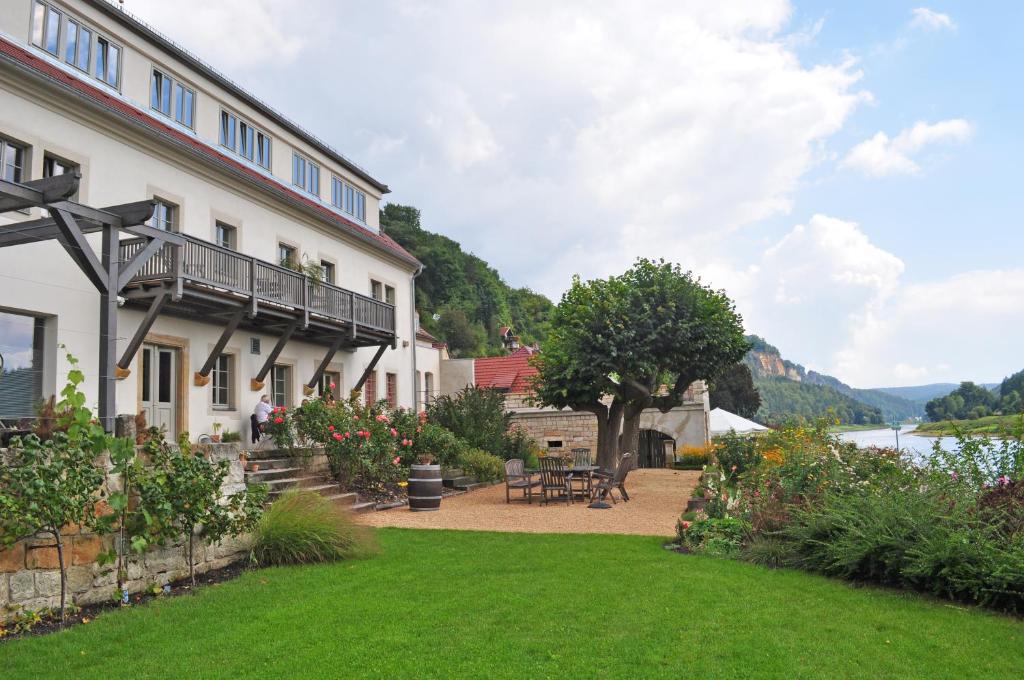 ein Gebäude mit einem Rasen neben einem Wasserkörper in der Unterkunft Elbterrasse Wehlen in Stadt Wehlen