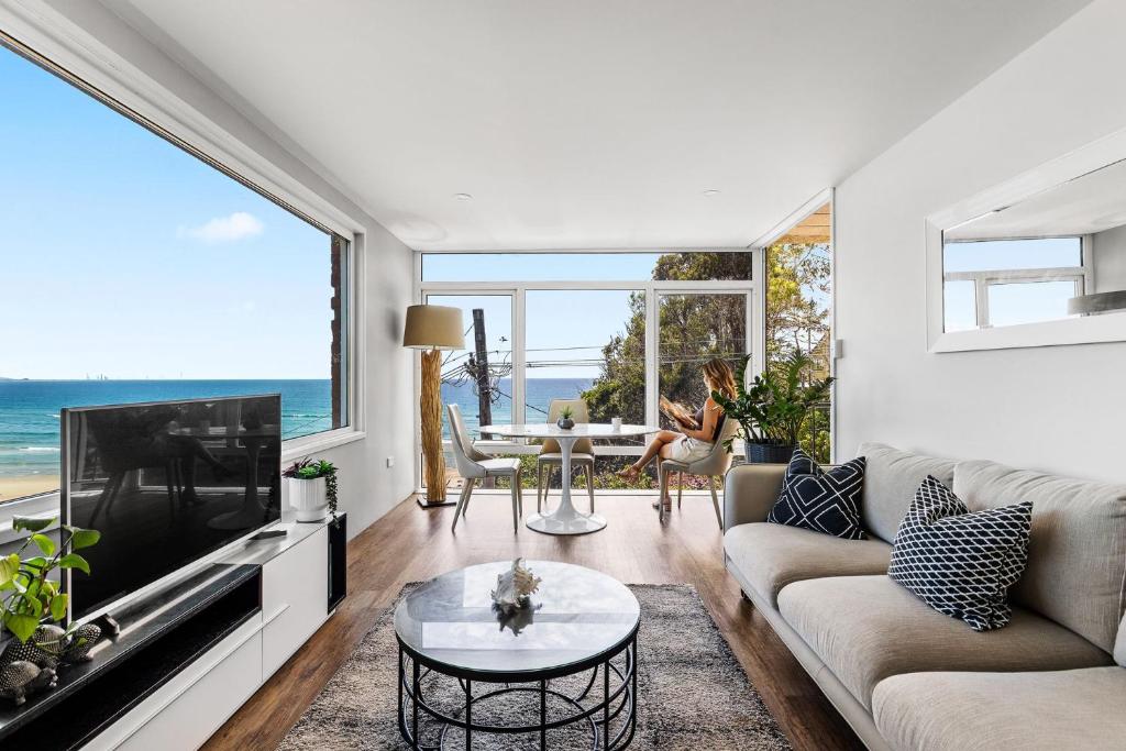 a living room with a couch and a tv and a table at Kirra Views in Gold Coast