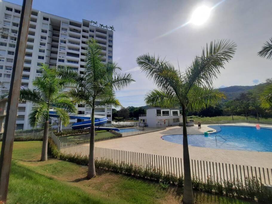 a swimming pool with palm trees in front of a building at Apartamento Recreativo in Santa Fe de Antioquia