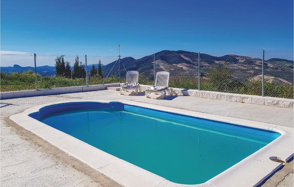 ein blauer Pool mit zwei Stühlen und einem Zaun in der Unterkunft Cozy Home In Olvera With Wifi in Olvera
