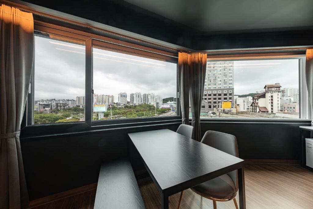 a dining room with a table and two windows at Brown Dot Hotel Seosan in Seosan