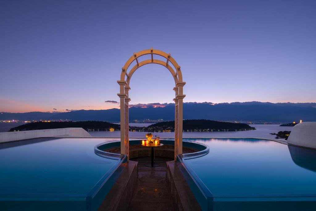 Una piscina infinita con fogata y un arco por la noche. en 大理圣托里尼半山海景酒店, en Dali