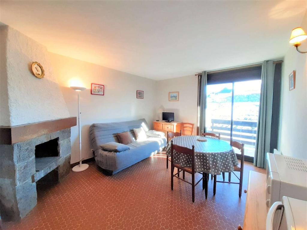 - un salon avec un canapé, une table et une cheminée dans l'établissement Studio confortable 4 pers, balcon, kitchenette équipée, PLA D'ADET - FR-1-457-250, à Saint-Lary-Soulan