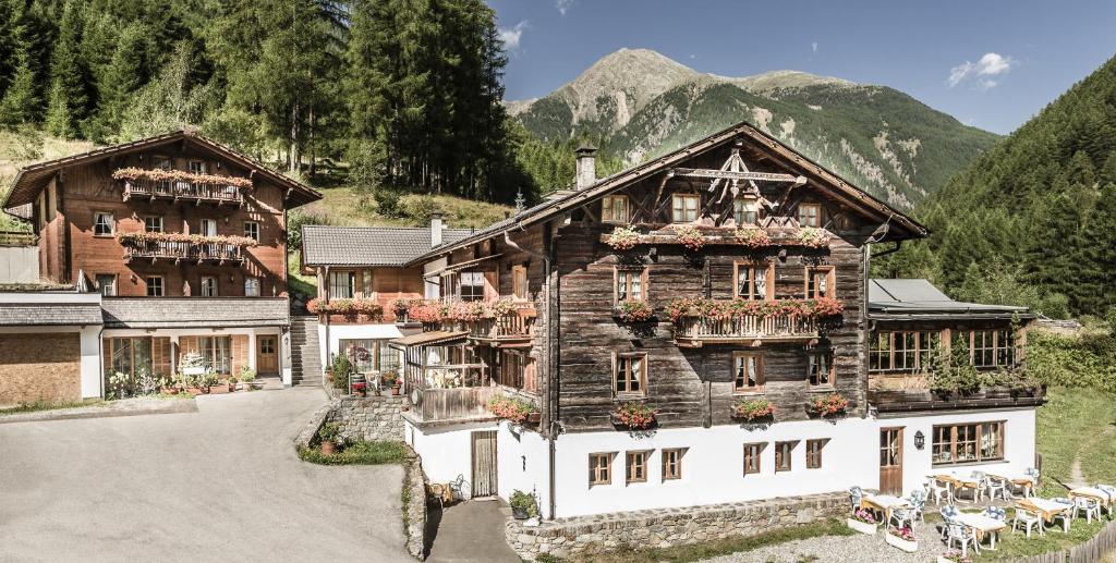 un grand bâtiment en bois avec des fleurs sur les fenêtres dans l'établissement Hotel Oberraindlhof, à Senales