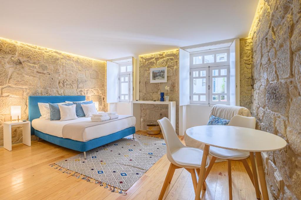 een slaapkamer met een bed en een tafel en stoelen bij PWHC Miragaia Apartments in Porto
