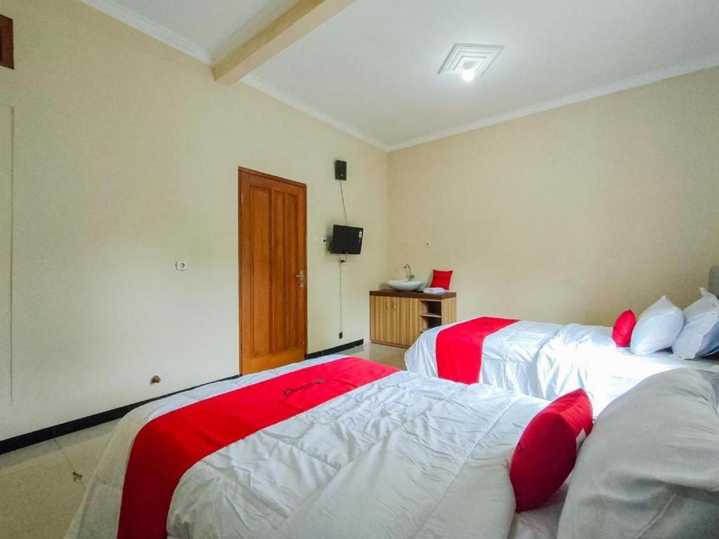 a bedroom with two beds with red and white sheets at RedDoorz @ Kisaran Kota in Kisaran