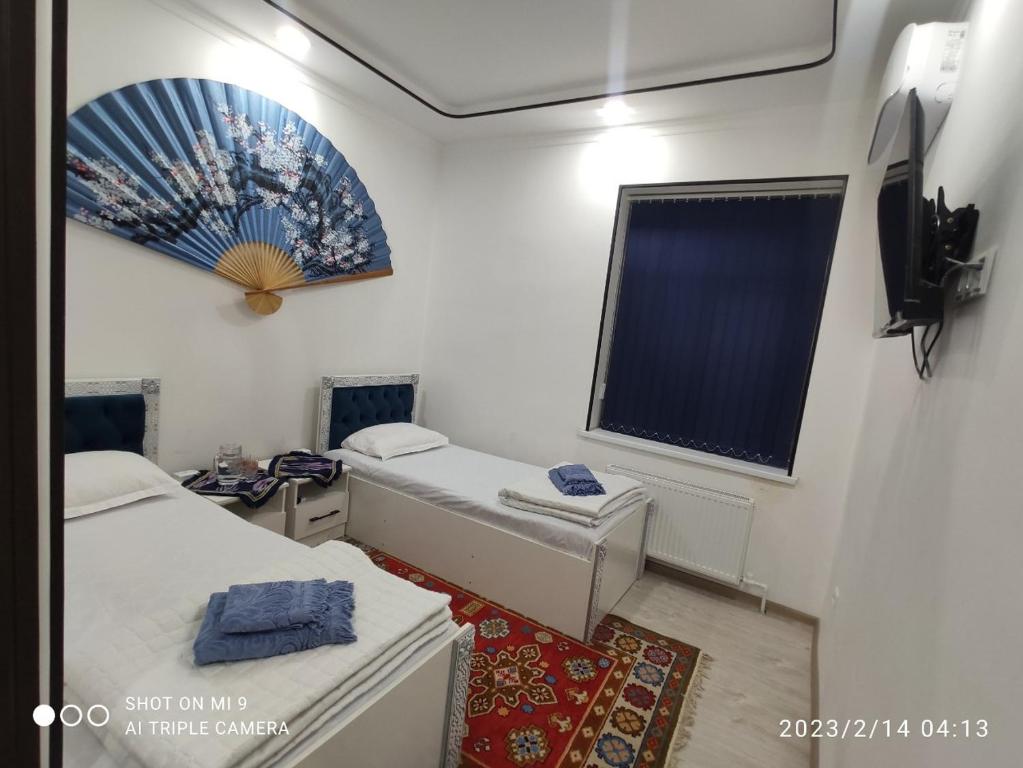 a small room with two beds and a window at KAMIR Guest House in Bukhara