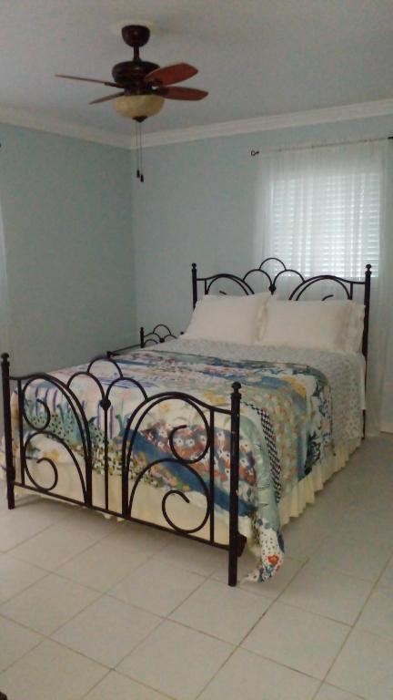 Bett in einem Schlafzimmer mit Deckenventilator in der Unterkunft Lynn's Cozy Cottage in Nassau