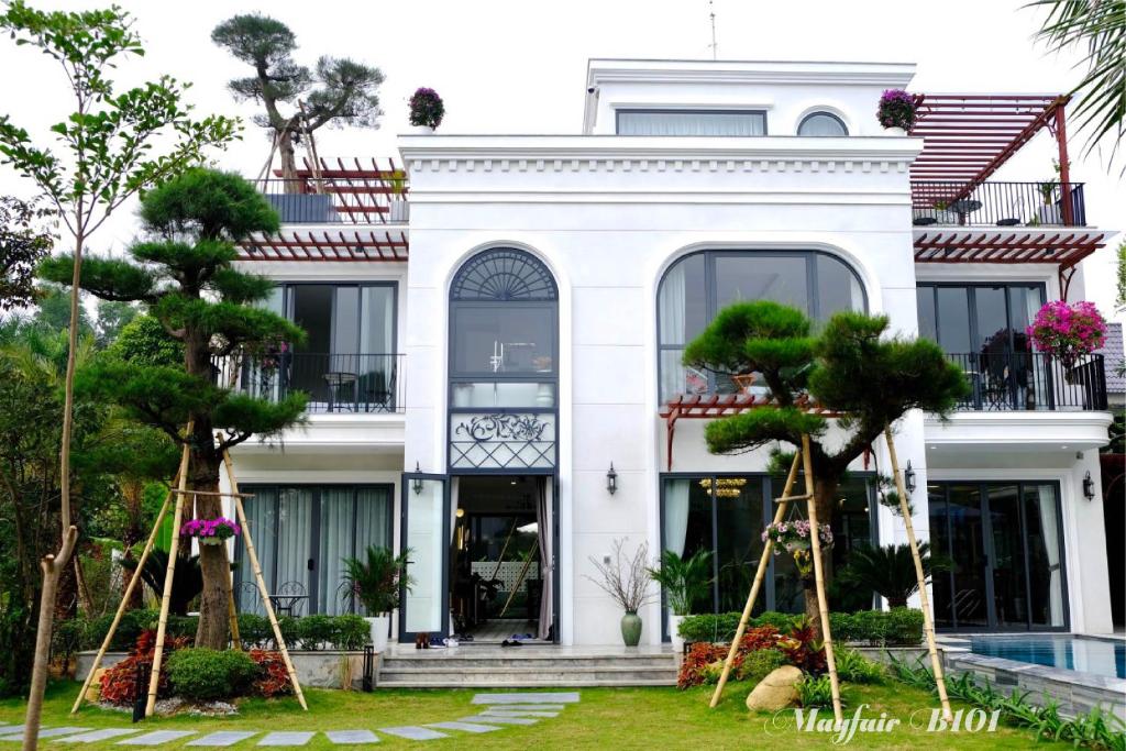 une maison blanche avec des arbres devant dans l'établissement Villa Mayfair B101 Đại Lải - 5 Phòng ngủ, à Thanh Cao