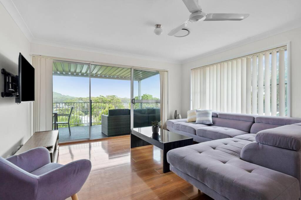 a living room with purple couches and a balcony at The Wreck Room Holiday House close to the Beach with Ample Boat Parking in Shoal Bay