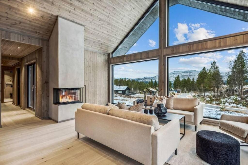 a living room with a fireplace and large windows at Brand new cabin at Hovden cross-country skiing in Hovden