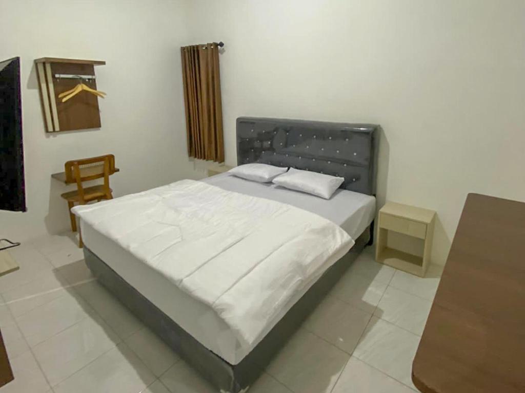 a bedroom with a large bed with white sheets at Nikie Guesthouse in Semarang