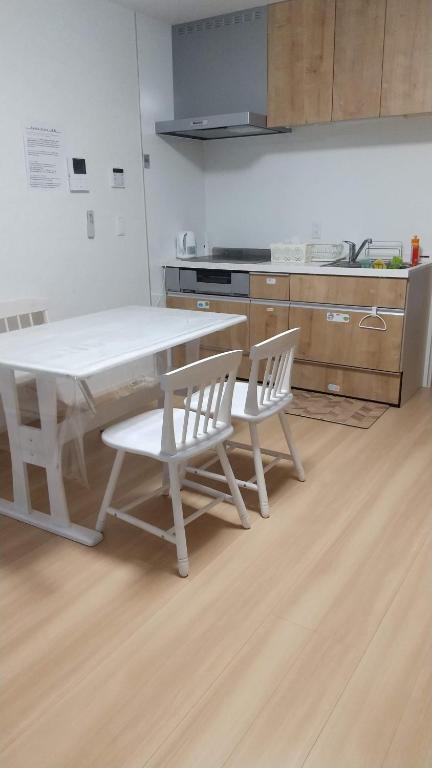 cocina con mesa blanca y 2 sillas blancas en メゾネットHIRAKU en Izumi-Sano