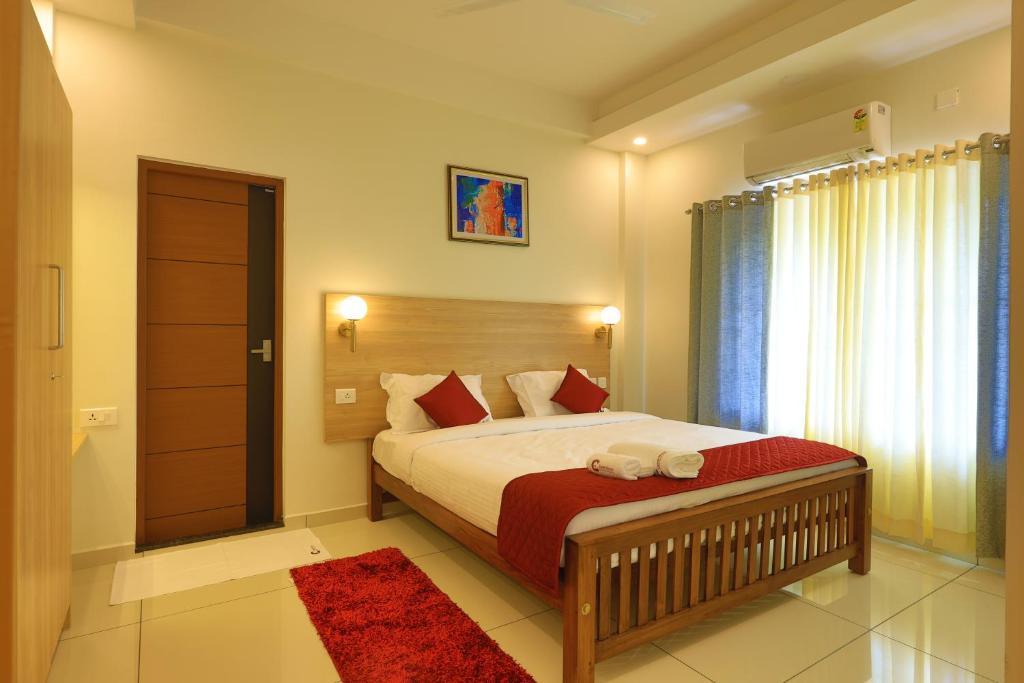 a bedroom with a large bed with a red blanket at Castle Brook Residential Homestay in Thiruvalla