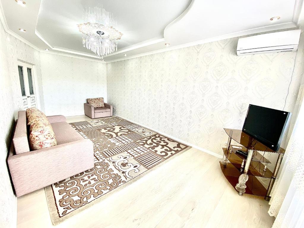 een woonkamer met een bank en een televisie bij Апартаменты 2 комнатная в новом ЖК in Aqtöbe