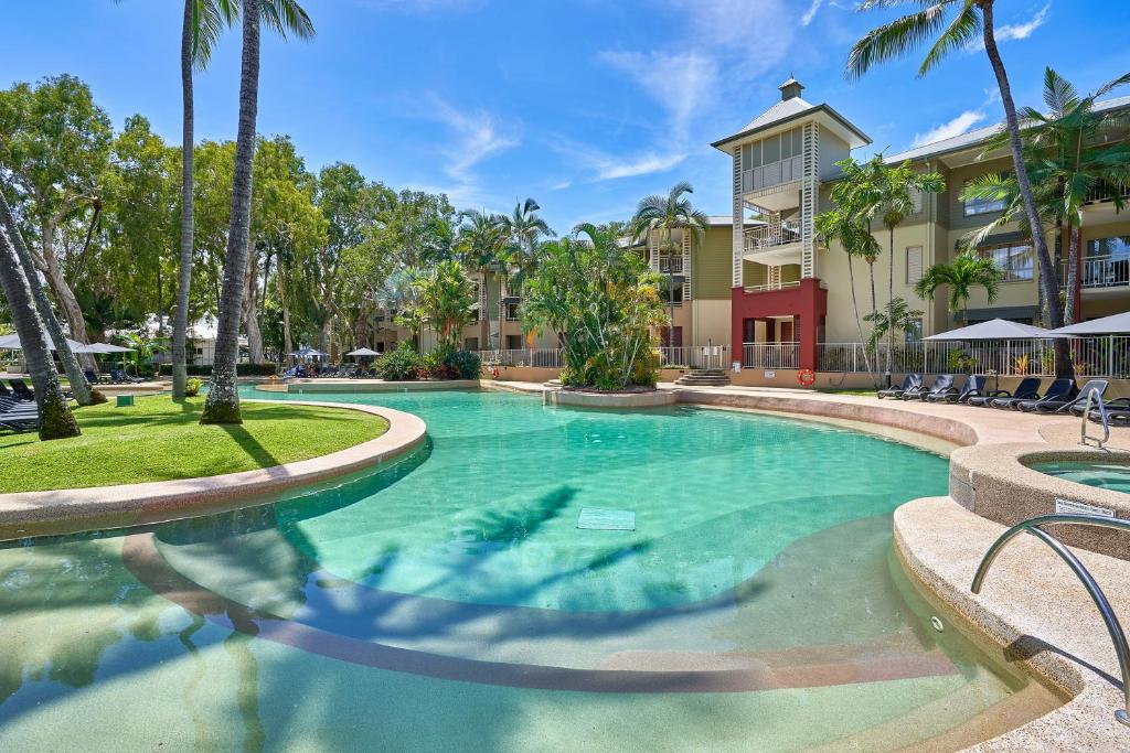 a swimming pool at a resort with palm trees at Amphora Laleuca Apartments Palm Cove in Palm Cove