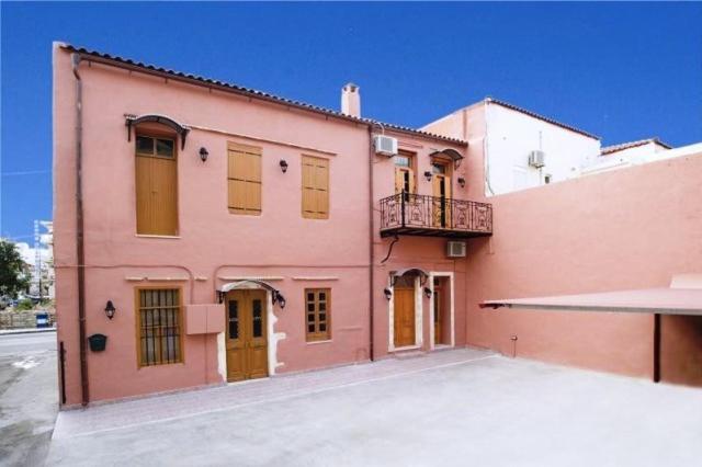 un edificio de color rosa con un balcón en el lateral. en Irene Maisonettes, en La Canea