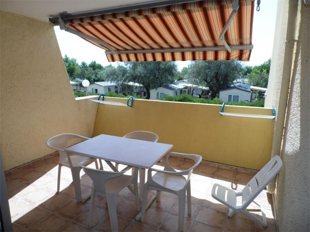 - une table et des chaises blanches sur la terrasse avec vue dans l'établissement Studio confortable avec terrasse, accès direct plage et parking privé - FR-1-326-506, à Marseillan
