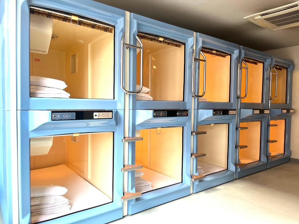 - un casier avec portes et fenêtres bleues dans l'établissement カプセル&サウナ日本 -男性専用 men only-, à Fukuyama