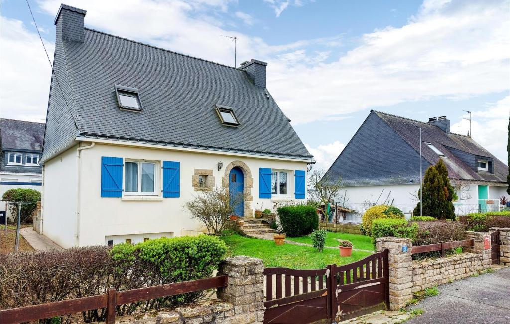 une maison blanche avec des fenêtres bleues et une clôture dans l'établissement Awesome Home In Hennebont With Wifi, à Hennebont