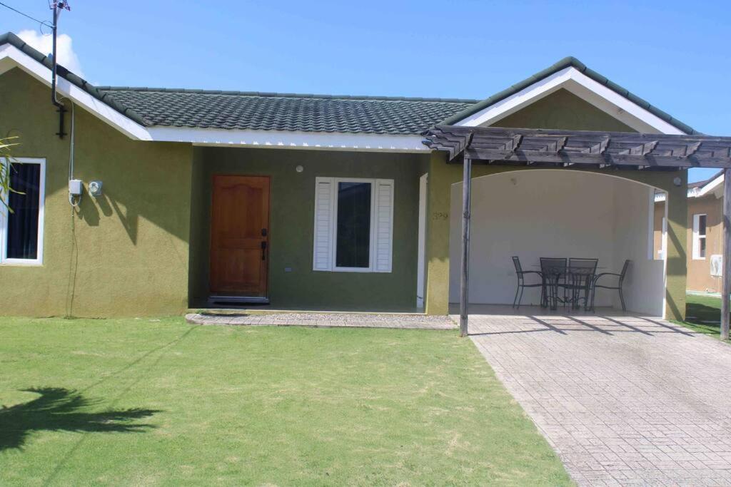 ein kleines grünes und weißes Haus mit einer Terrasse in der Unterkunft Hidden Escape,pool,gated,gym,air-conditioned, in Mammee Bay