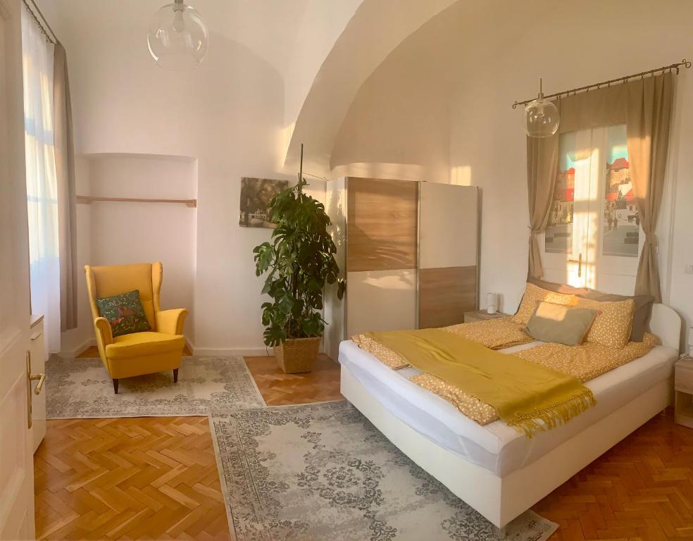 a bedroom with a bed and a yellow chair at Forst-Ház Apartman in Eger