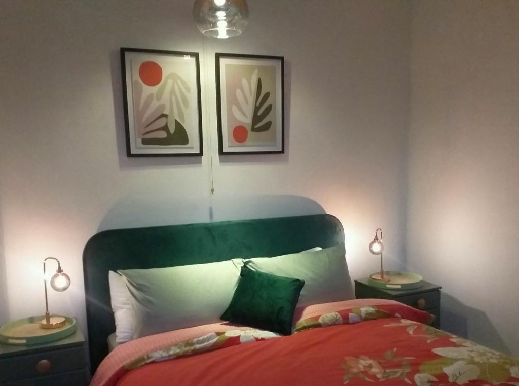 a bedroom with a bed with a green headboard and two lamps at JESMOND House B&B room 1 in Hull