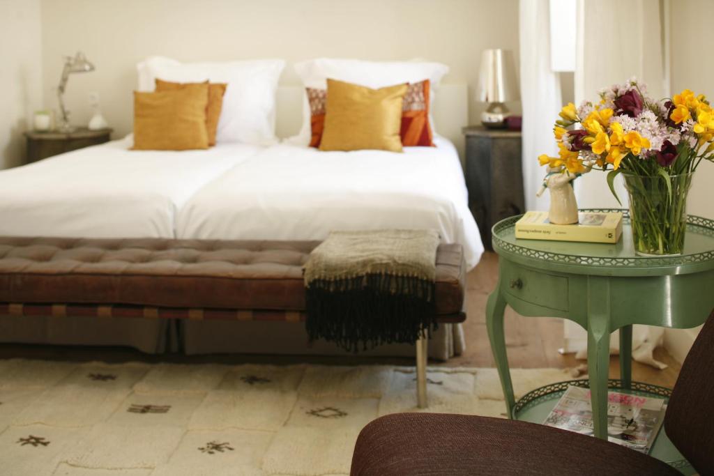 Casa das Janelas com Vista في لشبونة: غرفة نوم بسرير وطاولة مع إناء من الزهور