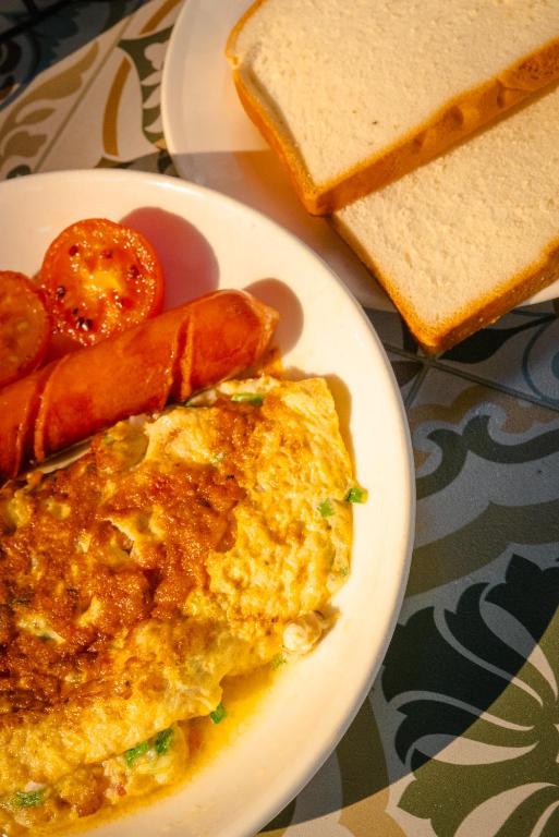 An omelette breakfast plate with sausage, tomatoes, and sliced bread.