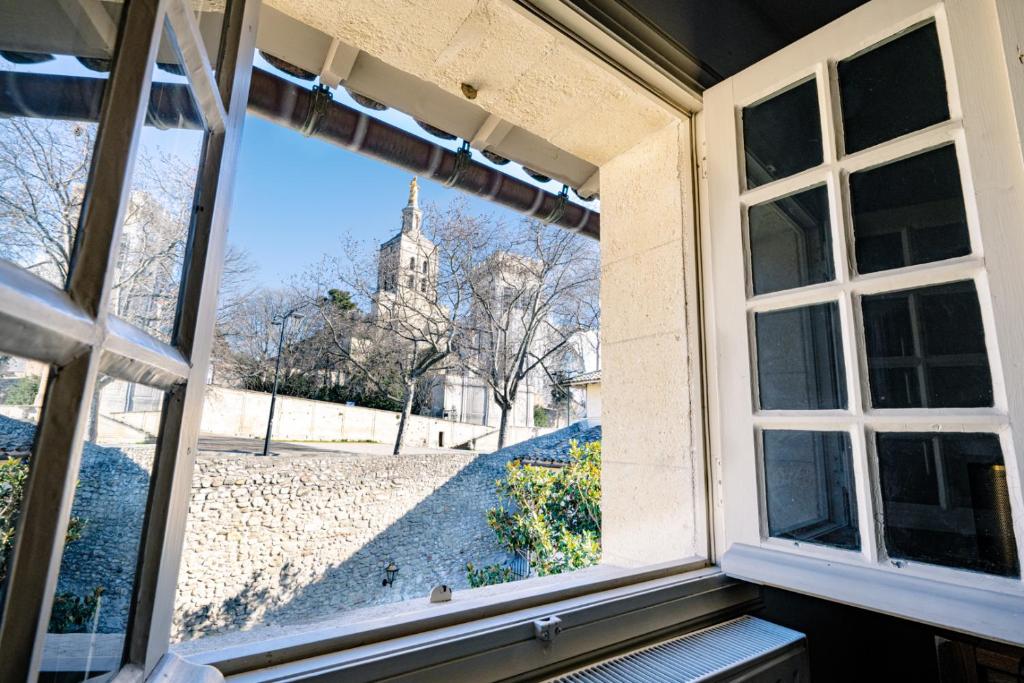 an open window with a view of a church at Appart Exceptionnel place du Palais des papes Wifi climatisation in Avignon