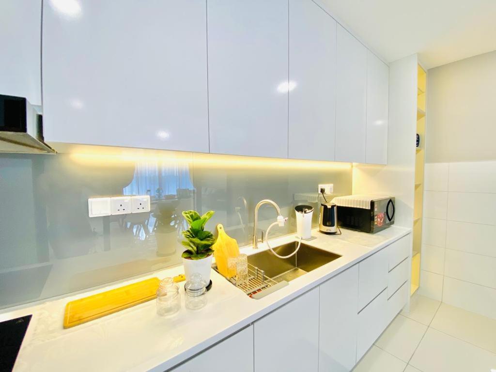 eine Küche mit weißen Schränken und einem Waschbecken in der Unterkunft Lovely Romantic HomeStay @Cheras in Kuala Lumpur