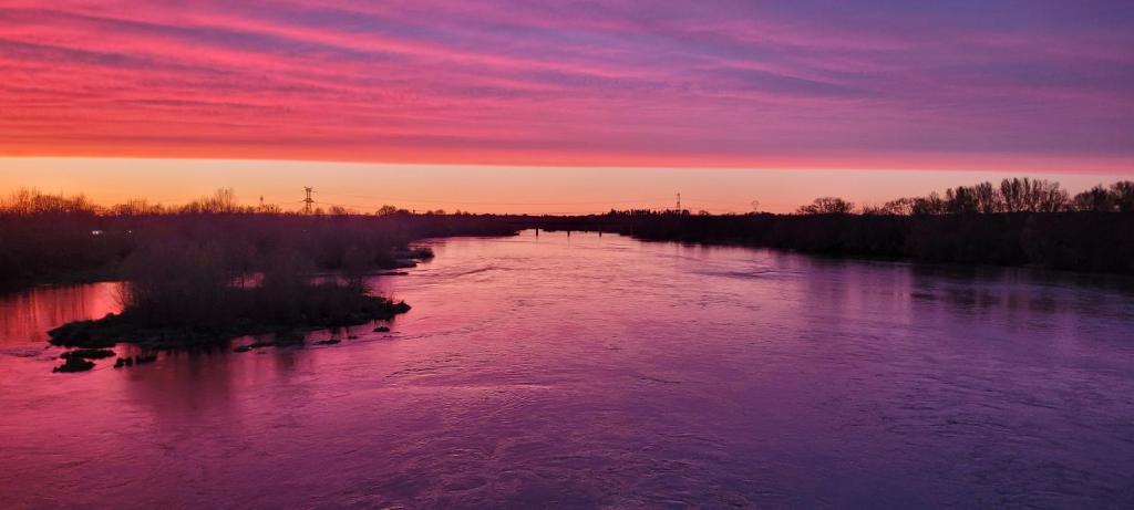 a river with a sunset in the background at Sur les bords de Loire in Montlouis-sur-Loire