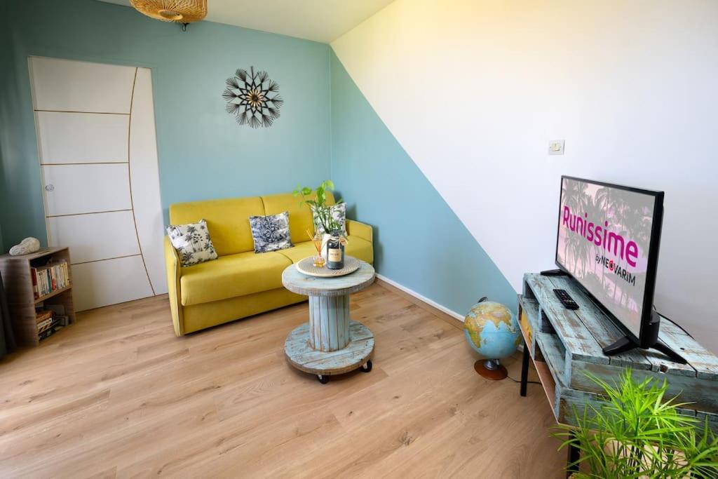 sala de estar con sofá amarillo y TV en Livianna, appartement 2 personnes avec une magnifique vue mer à Saint-Denis en Saint-Denis