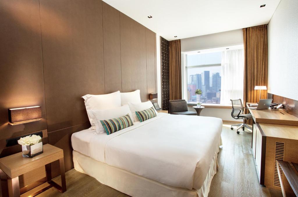 香港にあるNina Hotel Kowloon Eastの大きなベッドと机があるホテルの部屋