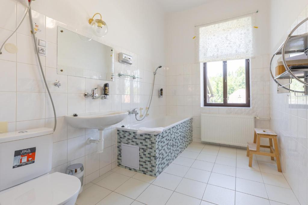biała łazienka z umywalką i wanną w obiekcie Hotel Amadeus w Czeskich Budziejowicach