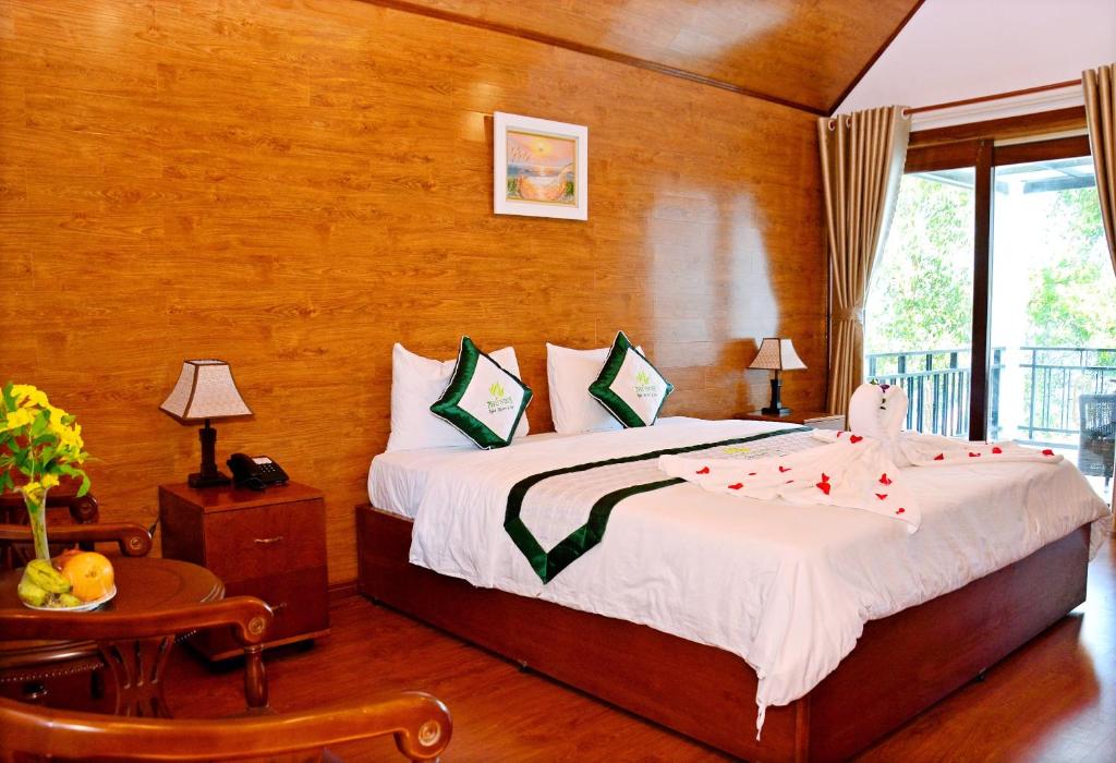 a bedroom with a bed and a table and a window at Phu Ninh Lake Resort & Spa in Tam Ky