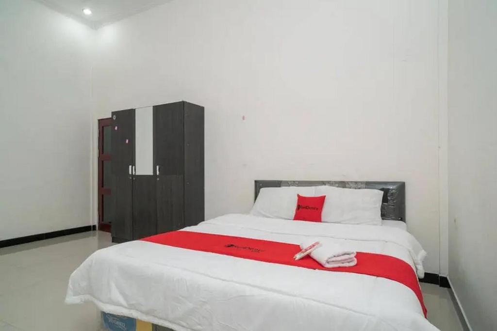 a bedroom with a large bed with a red blanket at RedDoorz Syariah Near Syamsudin Noor Airport 4 in Ulin