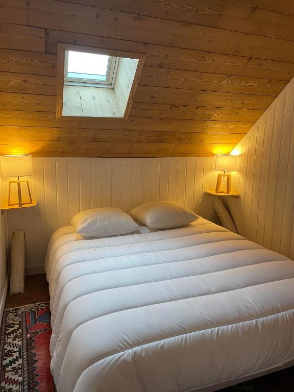 a bedroom with a large white bed with a window at Le Chalet de Carole in Cadéac
