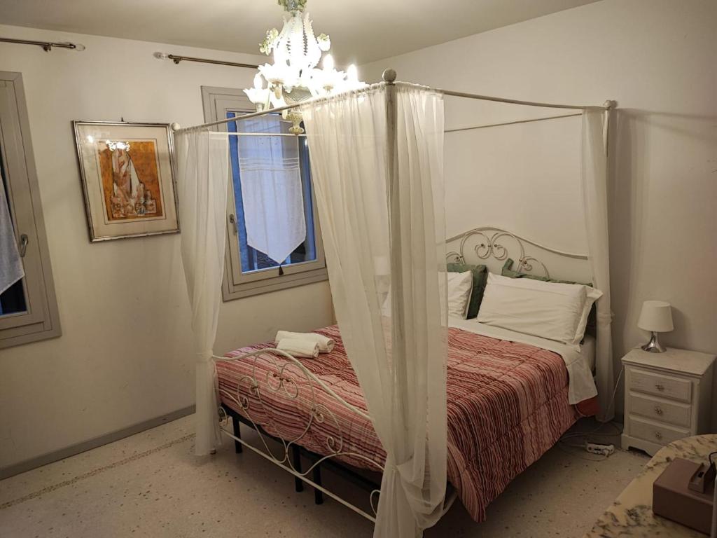 ein Schlafzimmer mit einem Himmelbett und einem Kronleuchter in der Unterkunft Love Gentile in Venedig