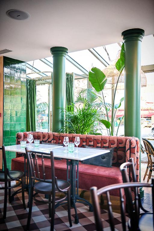 une table et des chaises dans un restaurant avec des colonnes vertes dans l'établissement Maison Eugenie, à Paris