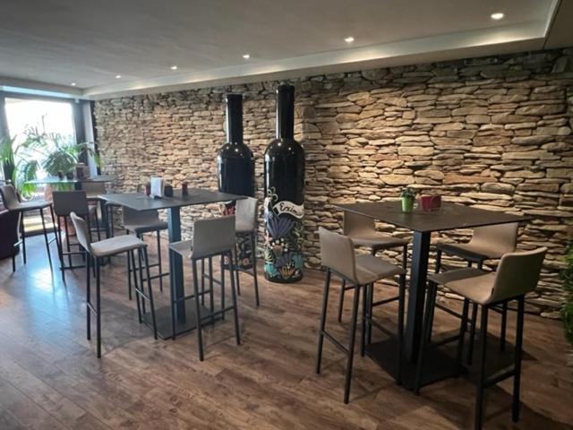 a restaurant with tables and chairs and a stone wall at Cave Beetschen in Bursins