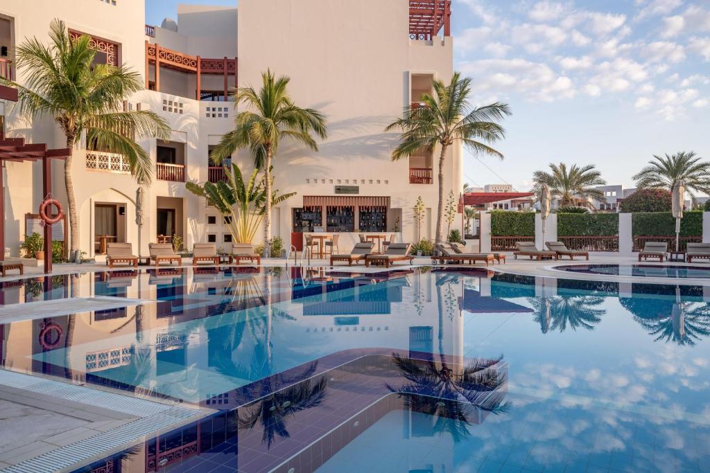 a swimming pool in front of a building with palm trees at Sifawy Boutique Hotel in As Sīfah